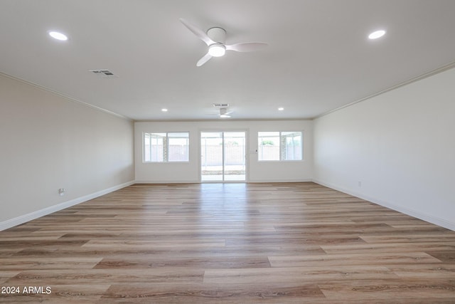 spare room with visible vents, light wood finished floors, ceiling fan, and ornamental molding