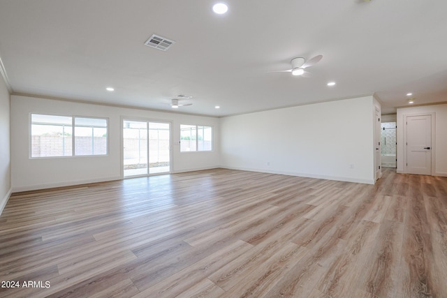 empty room with visible vents, ornamental molding, light wood-style floors, baseboards, and ceiling fan