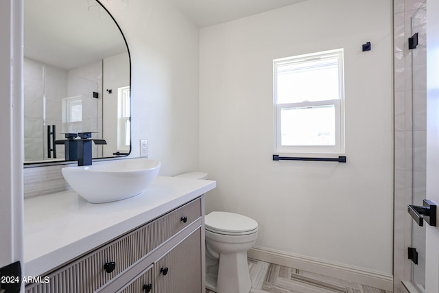 bathroom with tiled shower, vanity, and toilet