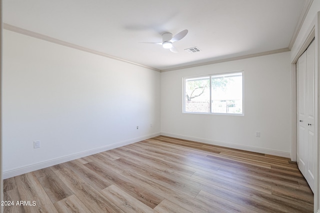 unfurnished bedroom featuring crown molding, ceiling fan, a closet, and light wood-type flooring