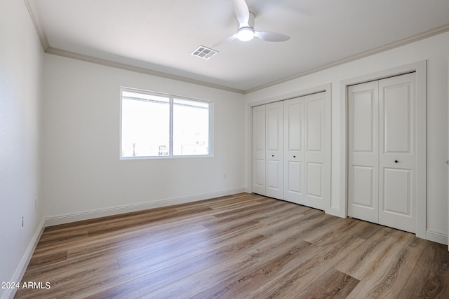 unfurnished bedroom with light wood-type flooring, ceiling fan, ornamental molding, and multiple closets