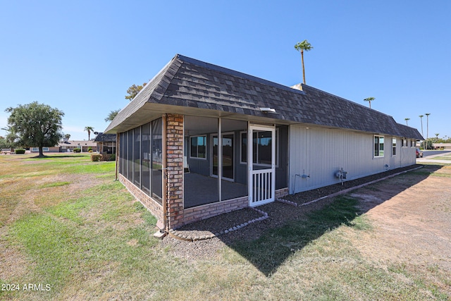 rear view of house with a yard and a sunroom