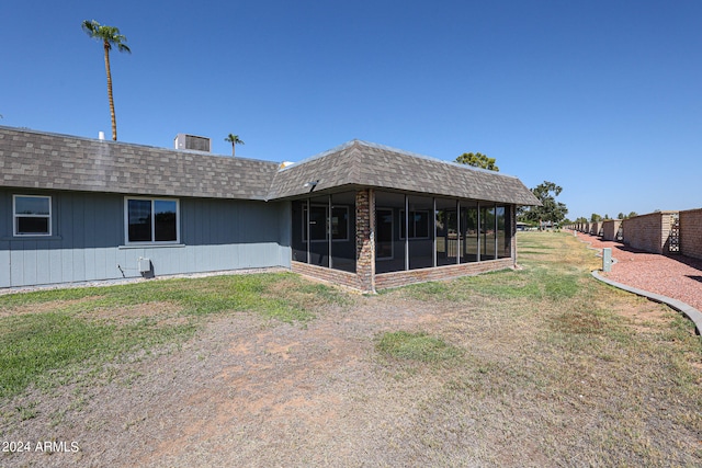 rear view of house with a sunroom and a yard