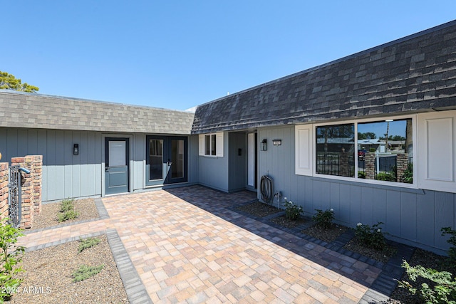 rear view of property featuring a patio area and roof with shingles