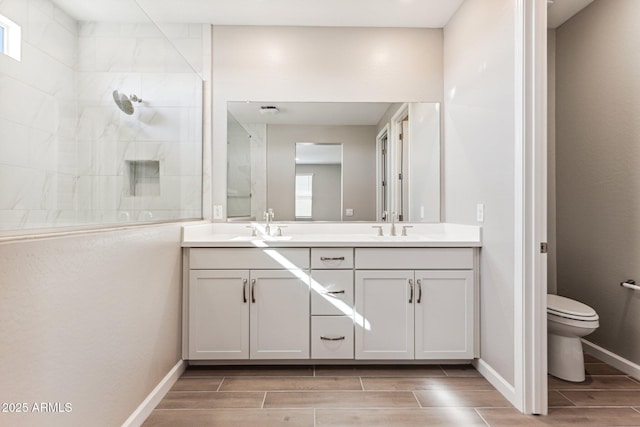 5844 E Covey Ln, Phoenix, AZ 85054 - bathroom with wood finish floors, tiled shower, double vanity, toilet, and baseboards