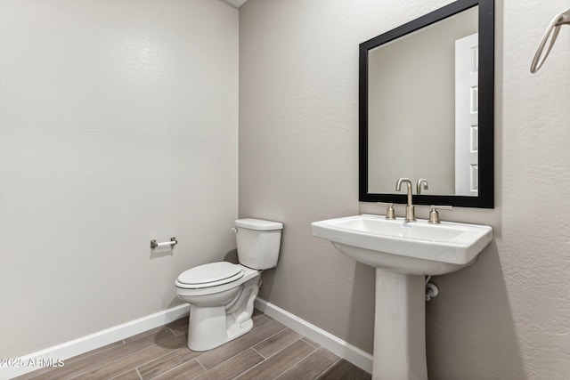 5844 E Covey Ln, Phoenix, AZ 85054 - half bath featuring wood finished floors, toilet, baseboards, and a sink