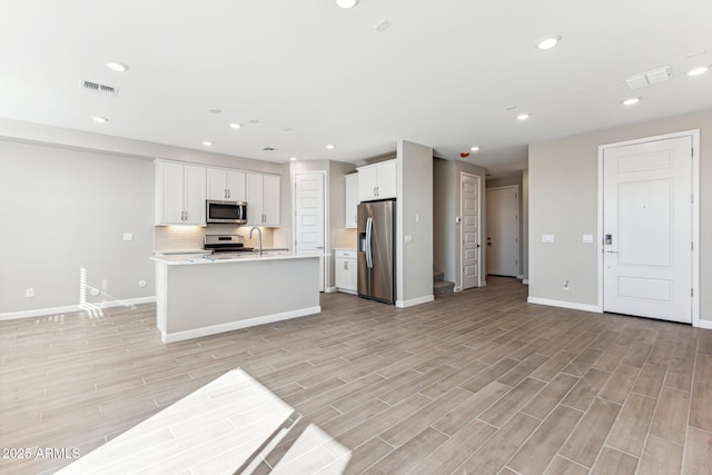 5844 E Covey Ln, Phoenix, AZ 85054 - kitchen with appliances with stainless steel finishes, baseboards, light countertops, open floor plan, and light wood-style flooring