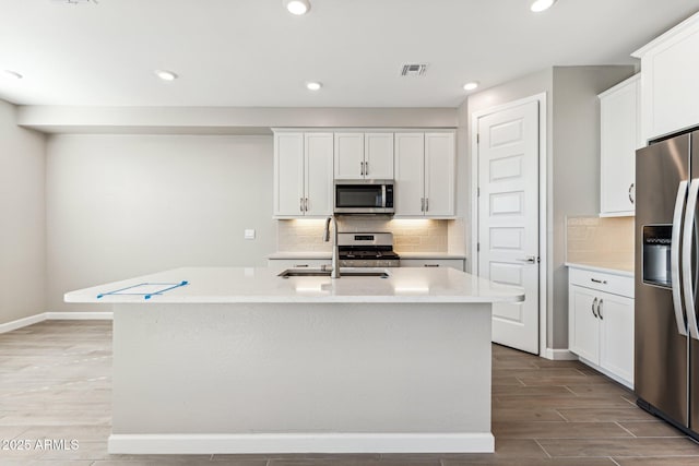 5844 E Covey Ln, Phoenix, AZ 85054 - kitchen featuring stainless steel appliances, light countertops, light wood-type flooring, a kitchen island with sink, and white cabinets