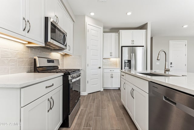 5844 E Covey Ln, Phoenix, AZ 85054 - kitchen featuring stainless steel appliances, a sink, wood finished floors, white cabinetry, and recessed lighting