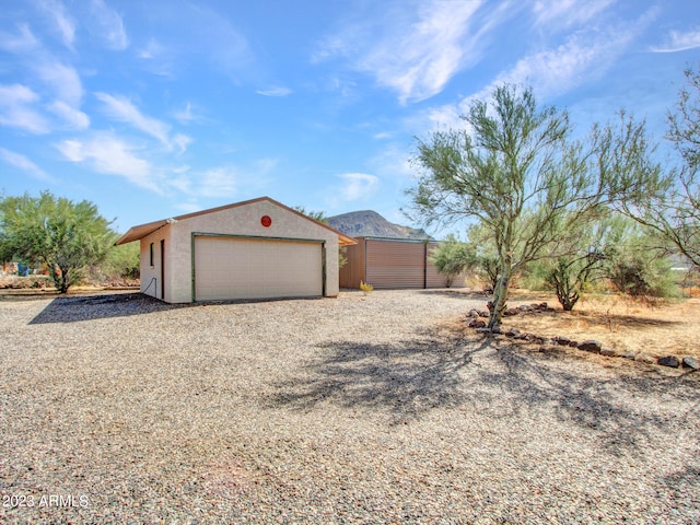 view of front of property with an outdoor structure, a mountain view, and a garage