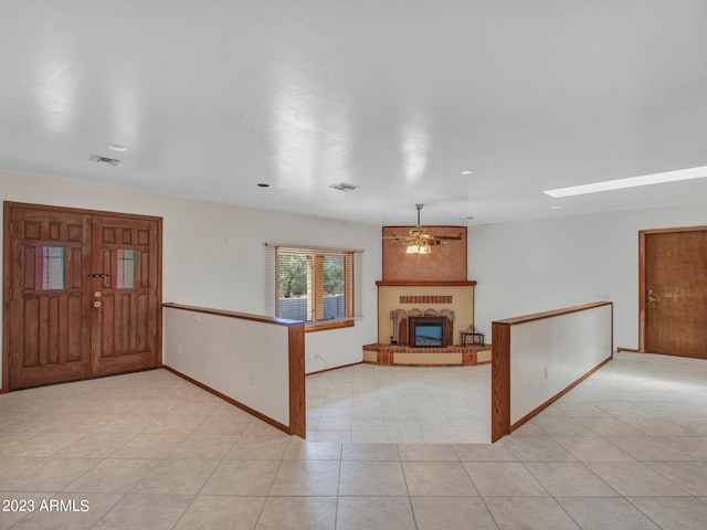 tiled foyer entrance featuring a fireplace and ceiling fan