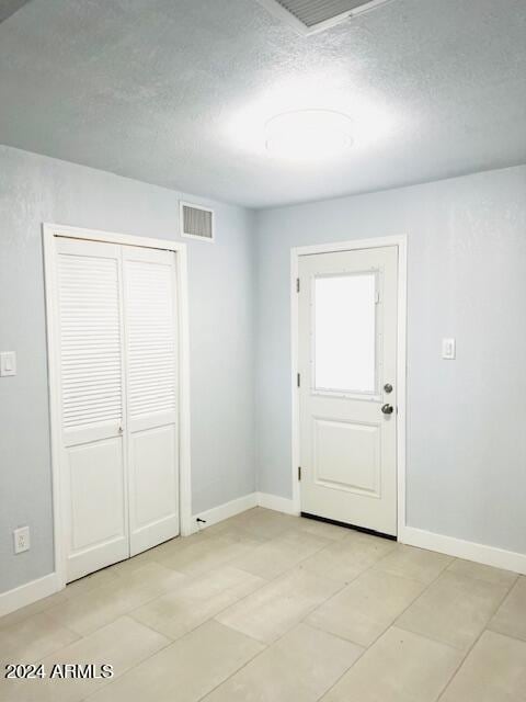 interior space with a textured ceiling and light tile patterned floors