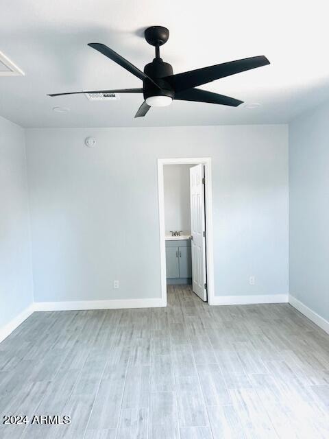 unfurnished bedroom with sink, ensuite bathroom, wood-type flooring, and ceiling fan