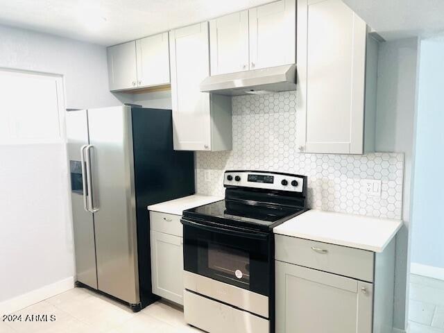 kitchen featuring high end fridge, range with electric cooktop, gray cabinetry, backsplash, and light tile patterned flooring