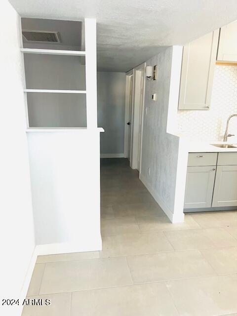 hall featuring sink and light tile patterned floors