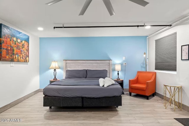 bedroom with light hardwood / wood-style flooring, rail lighting, and ceiling fan