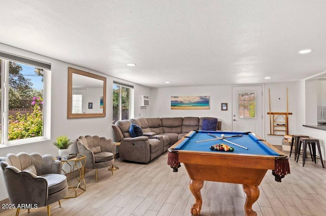 playroom with a wall mounted air conditioner, light hardwood / wood-style flooring, billiards, and a textured ceiling