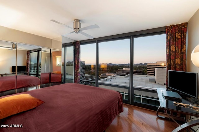 bedroom with floor to ceiling windows, wood finished floors, and a ceiling fan