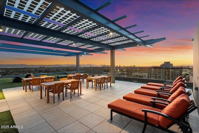 view of patio / terrace featuring a city view, a pergola, and outdoor dining space