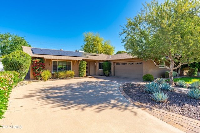 ranch-style house featuring a garage and solar panels