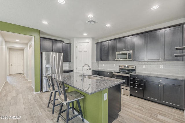 9934 E Orange Grove St, Florence, AZ 85132 - kitchen featuring appliances with stainless steel finishes, stone countertops, light wood-style floors, decorative backsplash, and recessed lighting