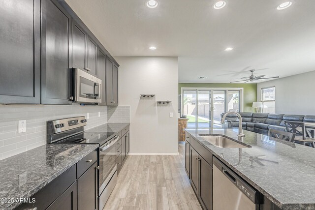 9934 E Orange Grove St, Florence, AZ 85132 - kitchen featuring appliances with stainless steel finishes, light wood-style flooring, recessed lighting, dark stone countertops, and a ceiling fan