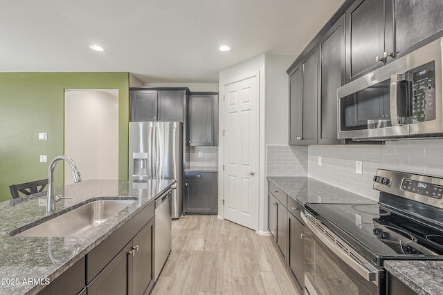 9934 E Orange Grove St, Florence, AZ 85132 - kitchen with stainless steel appliances, dark stone counters, light wood-style flooring, decorative backsplash, and recessed lighting