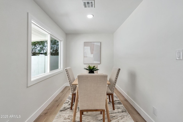 dining room with light wood finished floors, visible vents, and baseboards