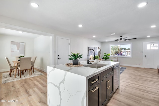 kitchen featuring light wood-type flooring, a sink, an island with sink, and recessed lighting