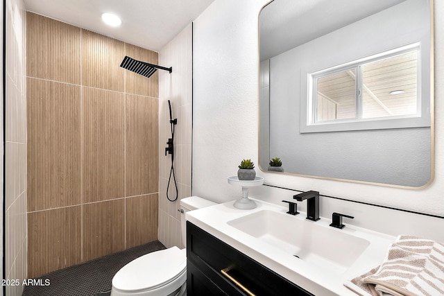 bathroom with tiled shower, vanity, and toilet