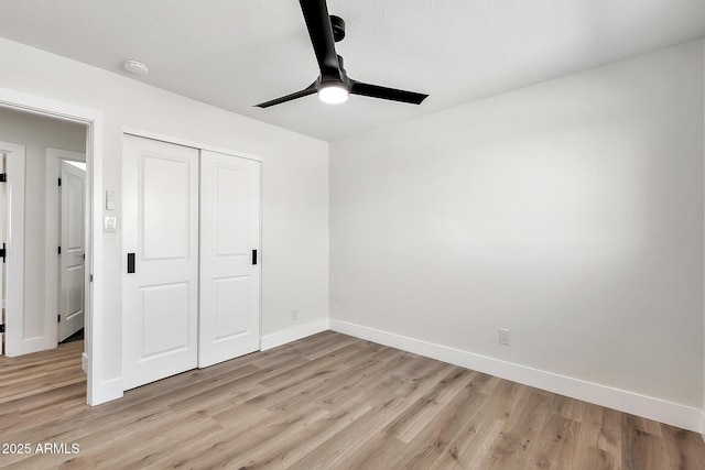 unfurnished bedroom with light wood-style floors, a closet, a textured ceiling, and baseboards