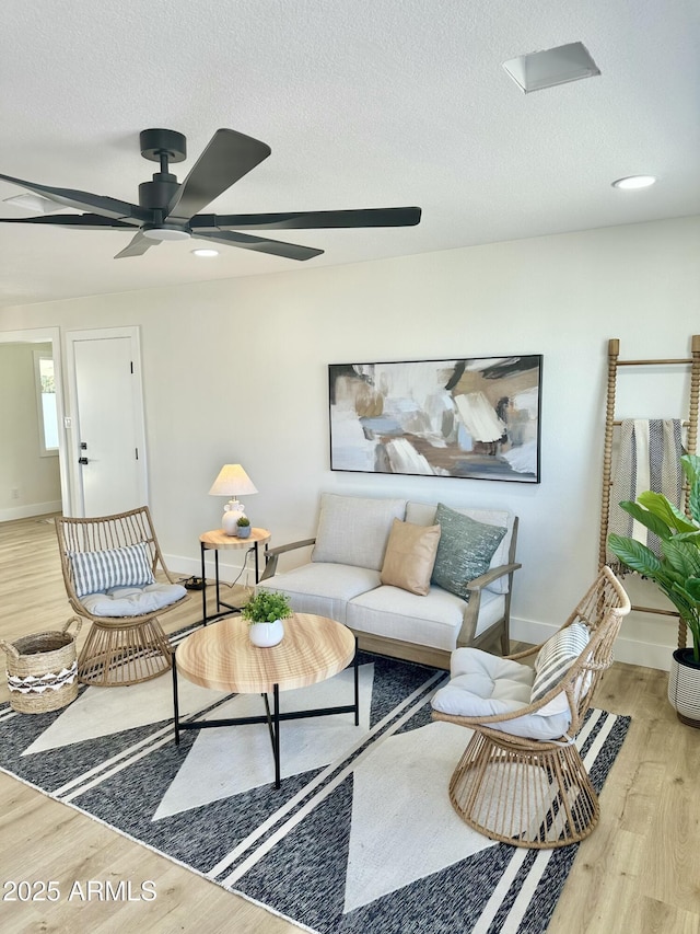 living room with a textured ceiling, baseboards, and wood finished floors