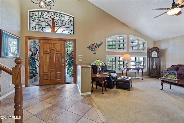 foyer entrance with ceiling fan with notable chandelier, carpet floors, and high vaulted ceiling