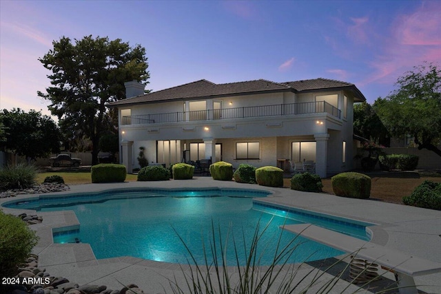 pool at dusk with a patio area