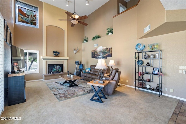 living room featuring carpet, a towering ceiling, and ceiling fan