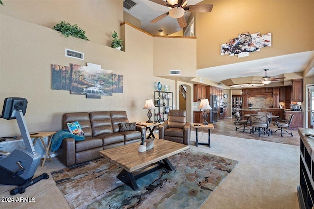 carpeted living room with ceiling fan and high vaulted ceiling