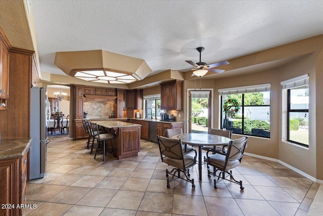 tiled dining area featuring ceiling fan with notable chandelier and a textured ceiling