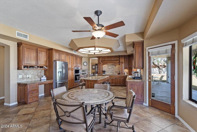 tiled dining area with a textured ceiling and ceiling fan