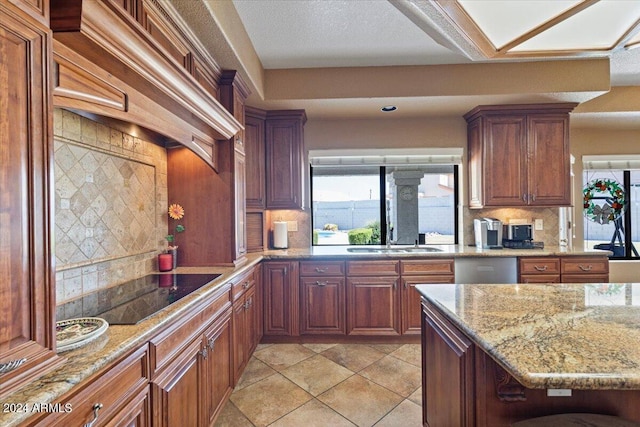 kitchen with decorative backsplash, light stone counters, custom exhaust hood, black electric cooktop, and sink