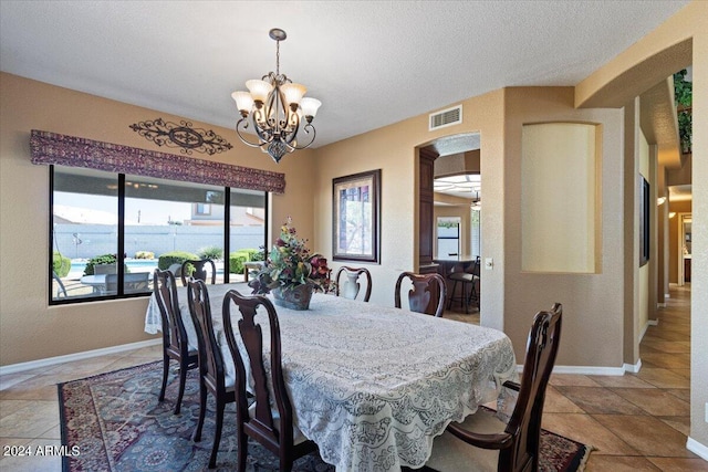 dining space with a textured ceiling and an inviting chandelier