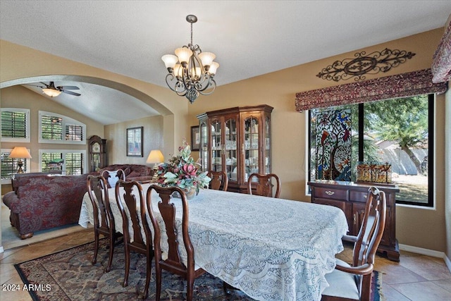 dining room with vaulted ceiling, tile patterned flooring, a textured ceiling, and ceiling fan with notable chandelier