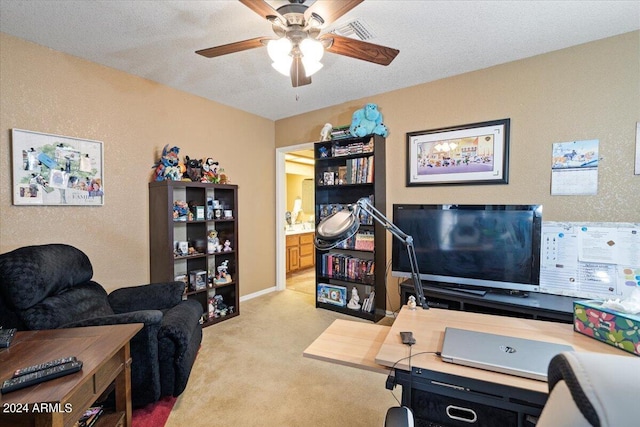 office area featuring a textured ceiling, light colored carpet, and ceiling fan