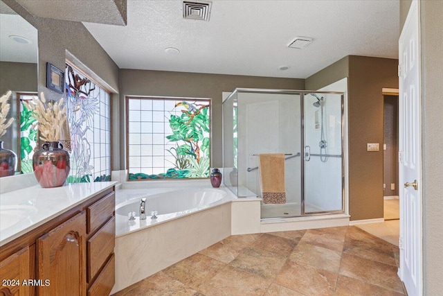 bathroom with a textured ceiling, vanity, and independent shower and bath