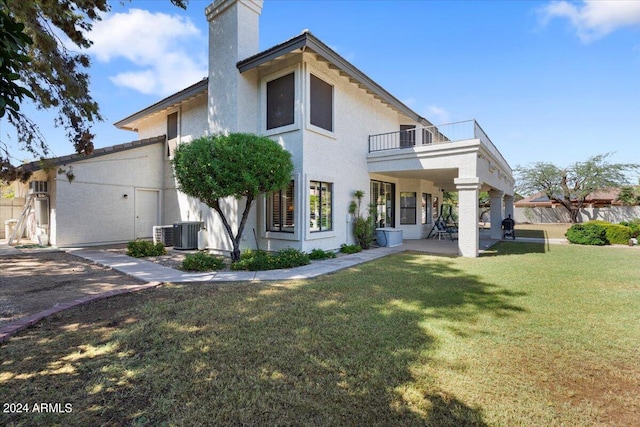 view of front of property with a patio area, a balcony, a front yard, and central AC