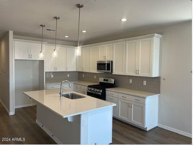 kitchen with a kitchen island with sink, white cabinets, sink, hanging light fixtures, and stainless steel appliances