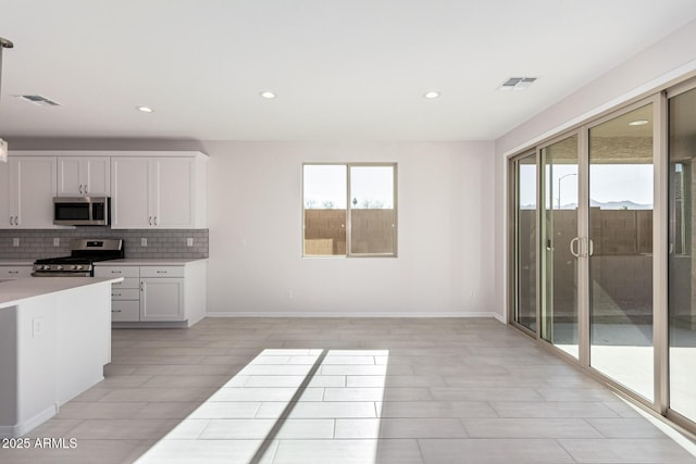 kitchen featuring decorative backsplash, appliances with stainless steel finishes, white cabinetry, and a wealth of natural light