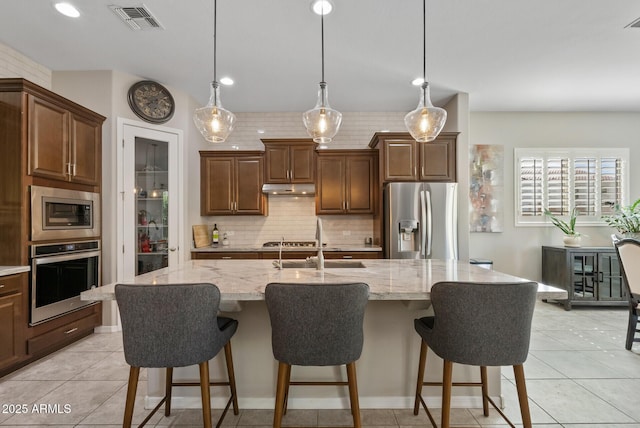 kitchen featuring a sink, stainless steel appliances, tasteful backsplash, under cabinet range hood, and visible vents