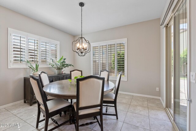 dining space featuring baseboards, light tile patterned flooring, and a chandelier