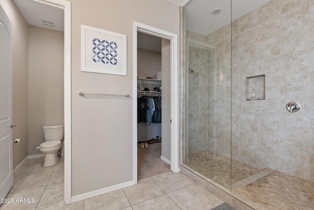 bathroom featuring tile patterned floors, toilet, and tiled shower