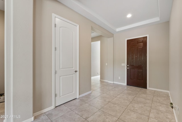 foyer with recessed lighting, baseboards, a raised ceiling, and light tile patterned floors